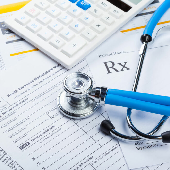 An image of health insurance form, stethoscope, and calculator.
